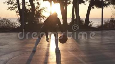 年轻的白种人女篮球运动员在球场上运球和练习球处理技巧。 早晨的黄昏，阳光照耀